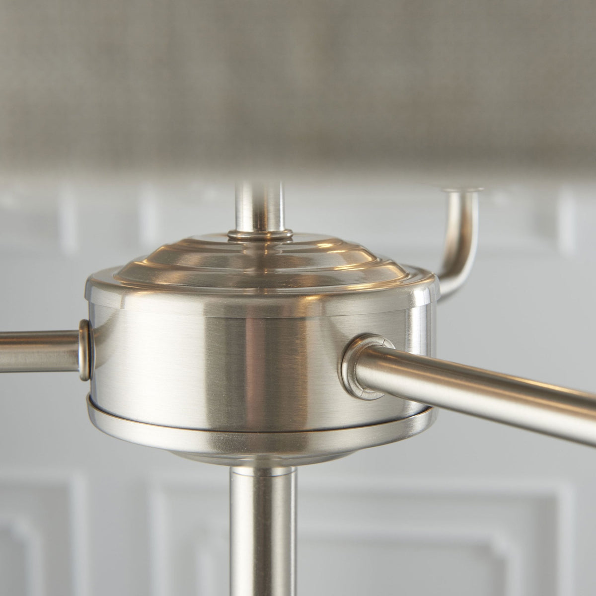 Close-up of the brushed nickel base and arms supporting the shade of a floor lamp.