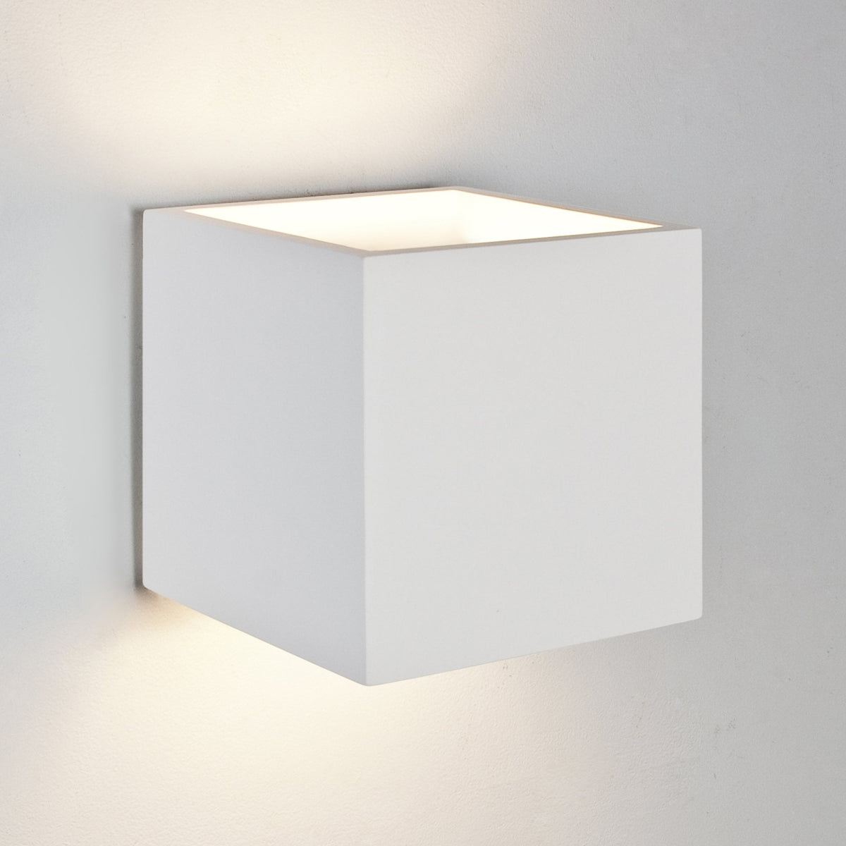 White cube-shaped wall light with light emitting from top and bottom, mounted on a light grey wall