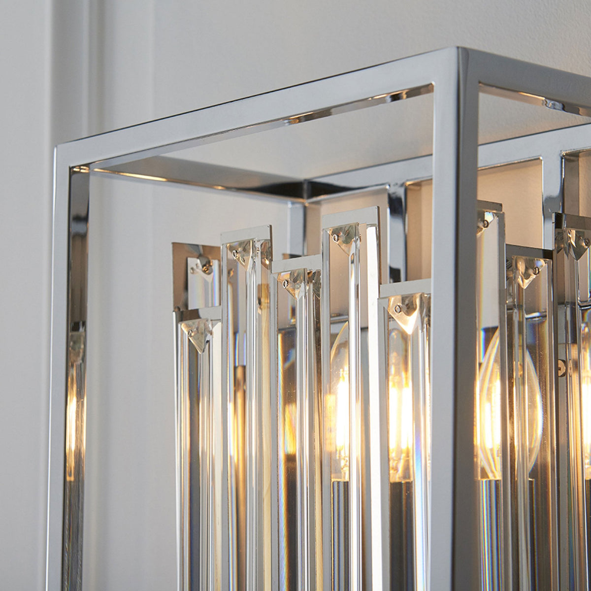 Close-up of a chrome and crystal light fixture with illuminated bulbs.