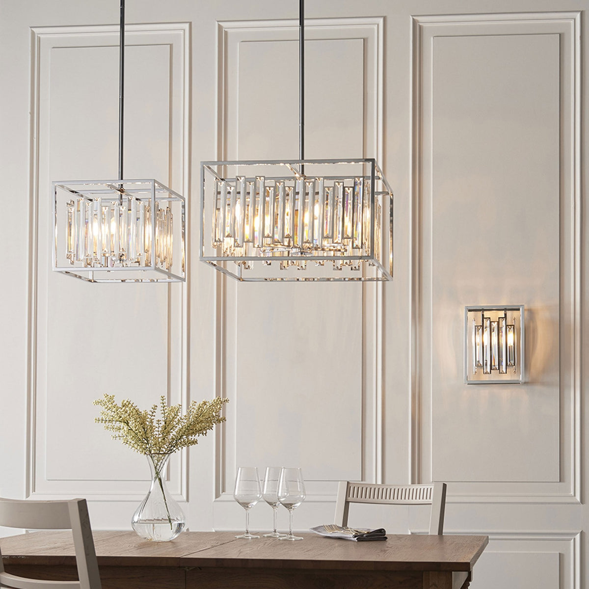 Two rectangular chrome and crystal pendant lights hang over a dining table with a matching wall light.