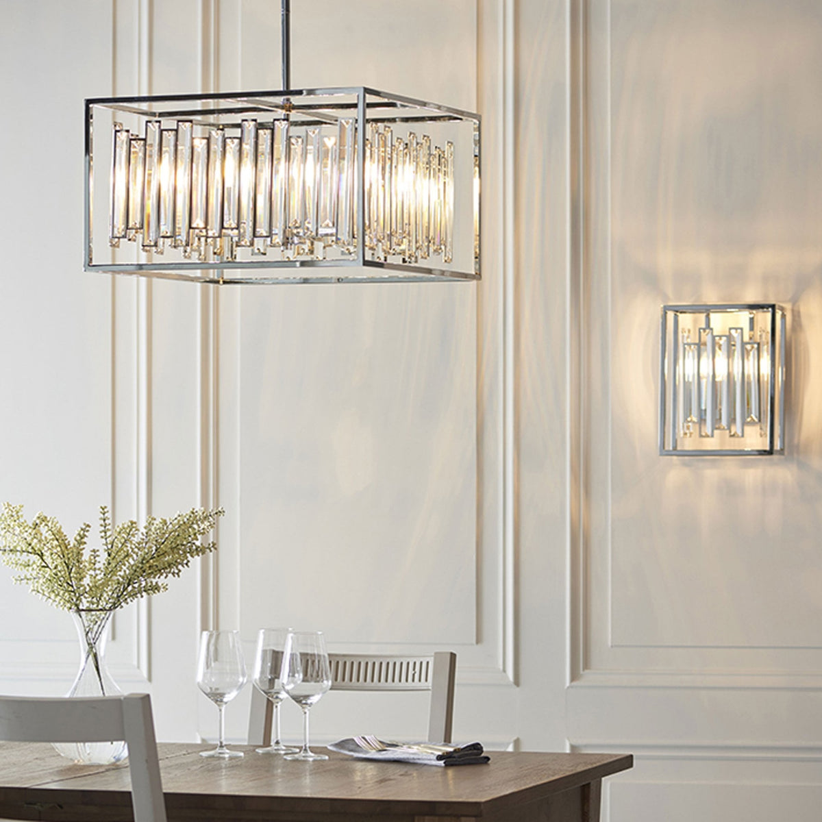 Rectangular chrome and crystal pendant light over a dining table, with a matching wall light.