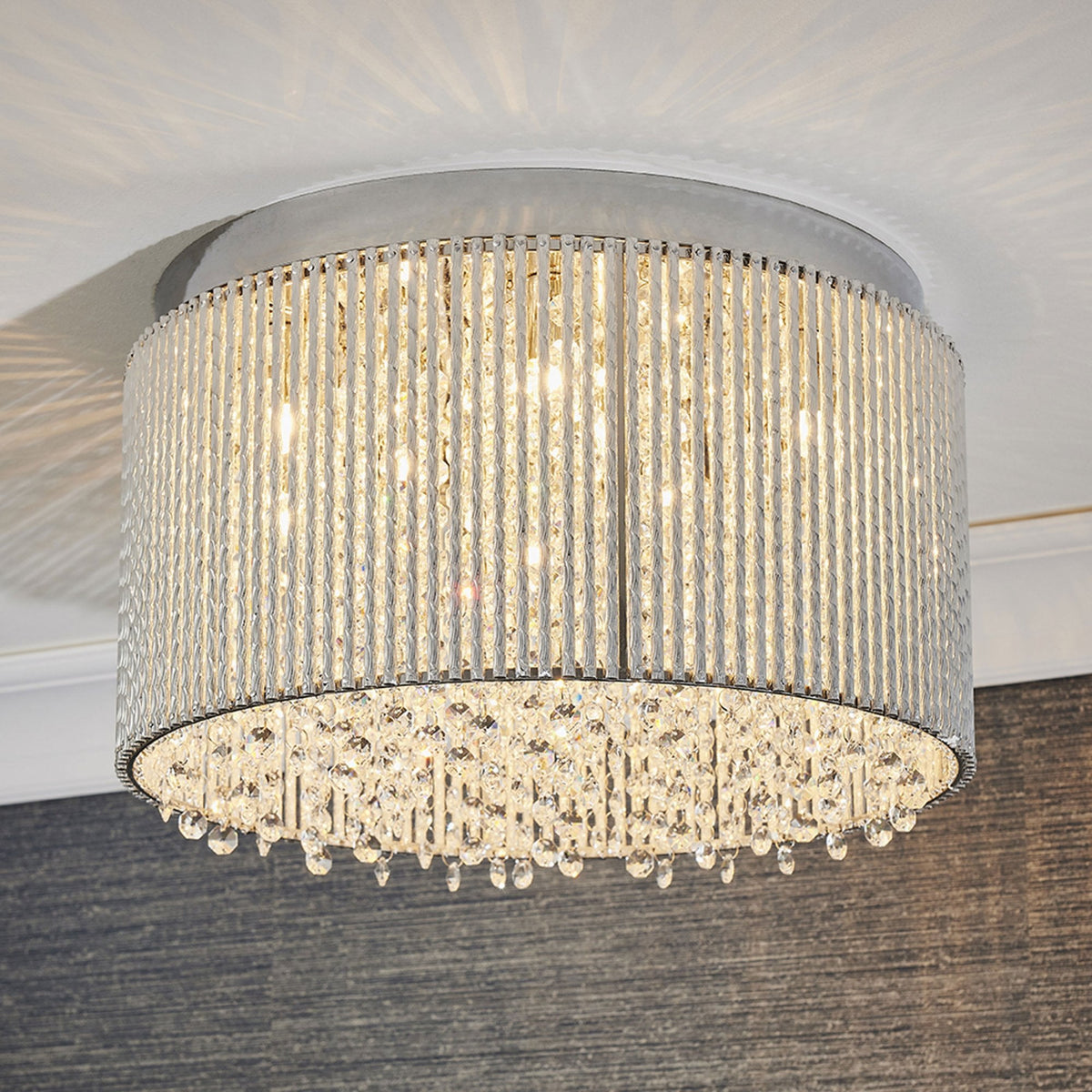 A round, silver flush mount ceiling light with a textured band and dangling crystal accents.