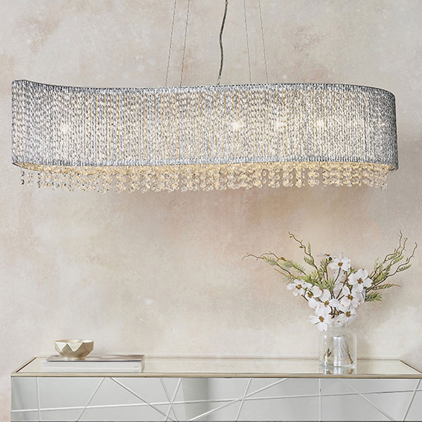 Wavy crystal chandelier with a textured silver shade and dangling clear crystals, illuminating a modern console table.