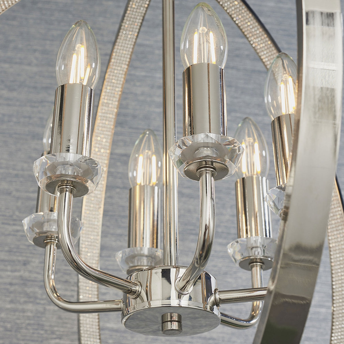 Close-up of the polished nickel chandelier's five candle-style bulbs with crystal accents.