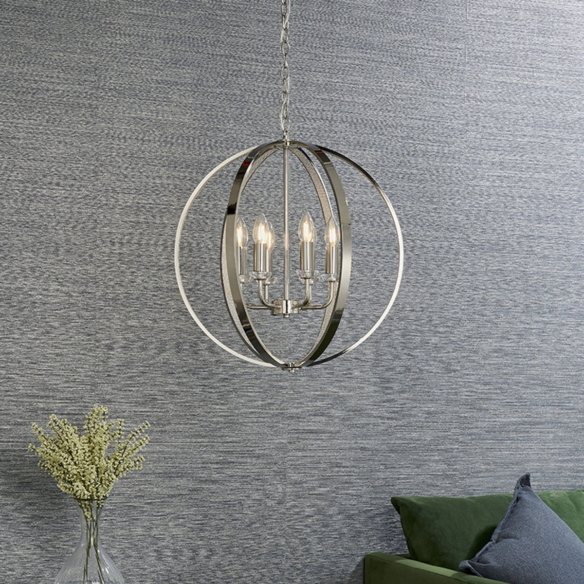 Polished nickel chandelier hanging in a room with a textured gray wall and a green sofa.