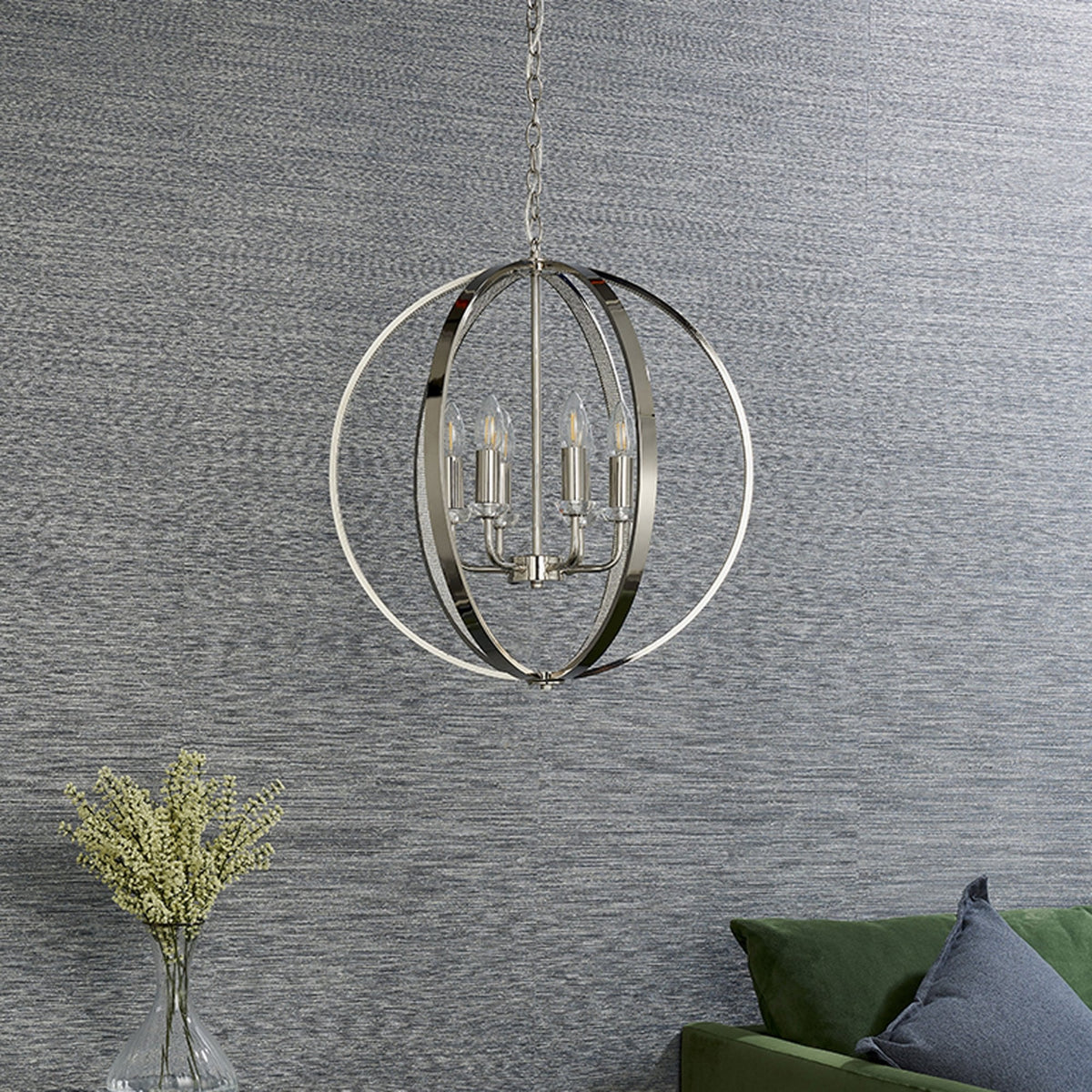 Polished nickel chandelier hanging in a room with a textured gray wall and a green sofa.