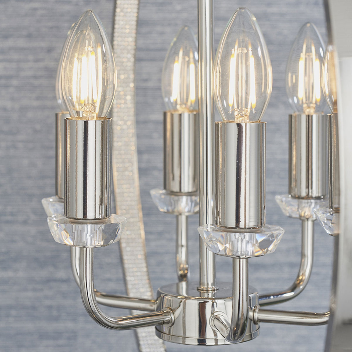 Close-up of the chandelier's five candle-style bulbs with crystal bases and polished nickel arms.