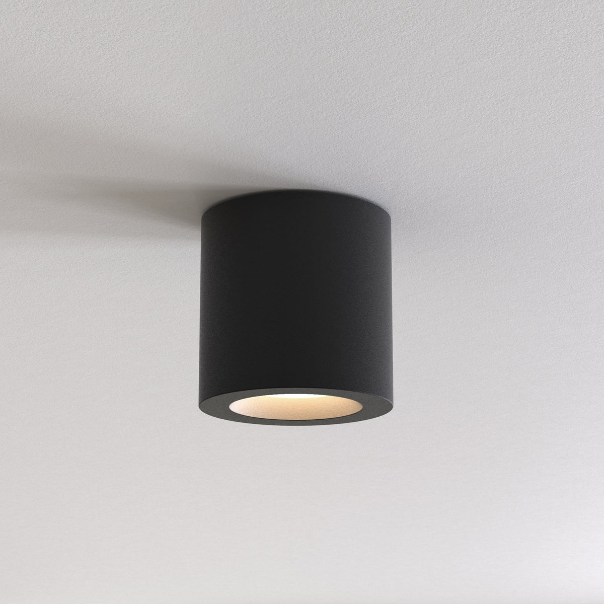 Black cylindrical ceiling light fixture with a warm glow