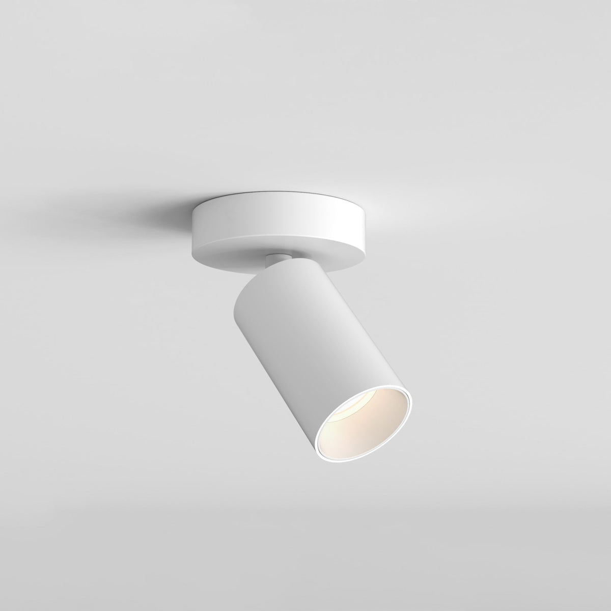 White cylindrical ceiling spotlight with a warm glow, angled downwards against a light grey background