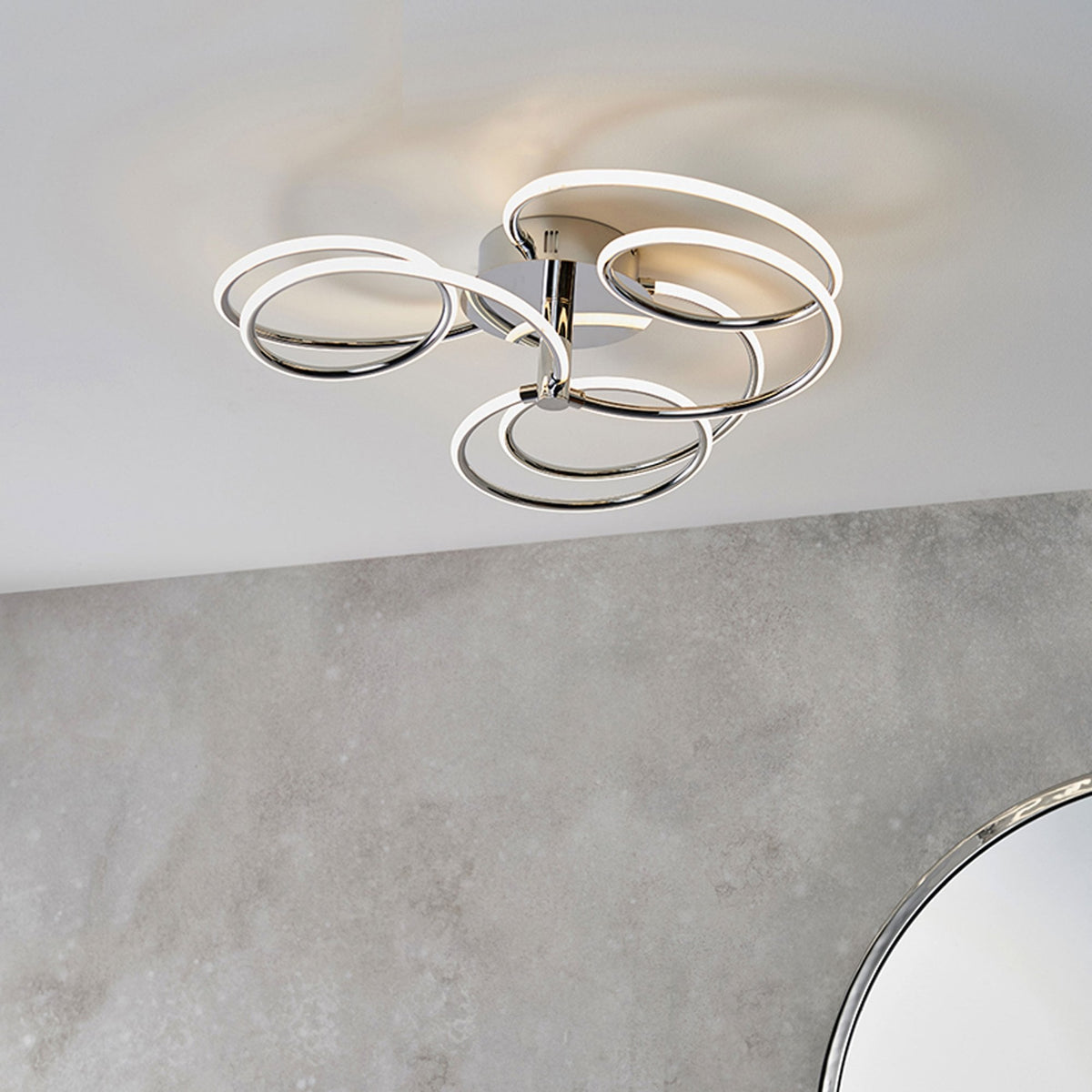 Modern chrome ceiling light with five illuminated rings, installed on a white ceiling.