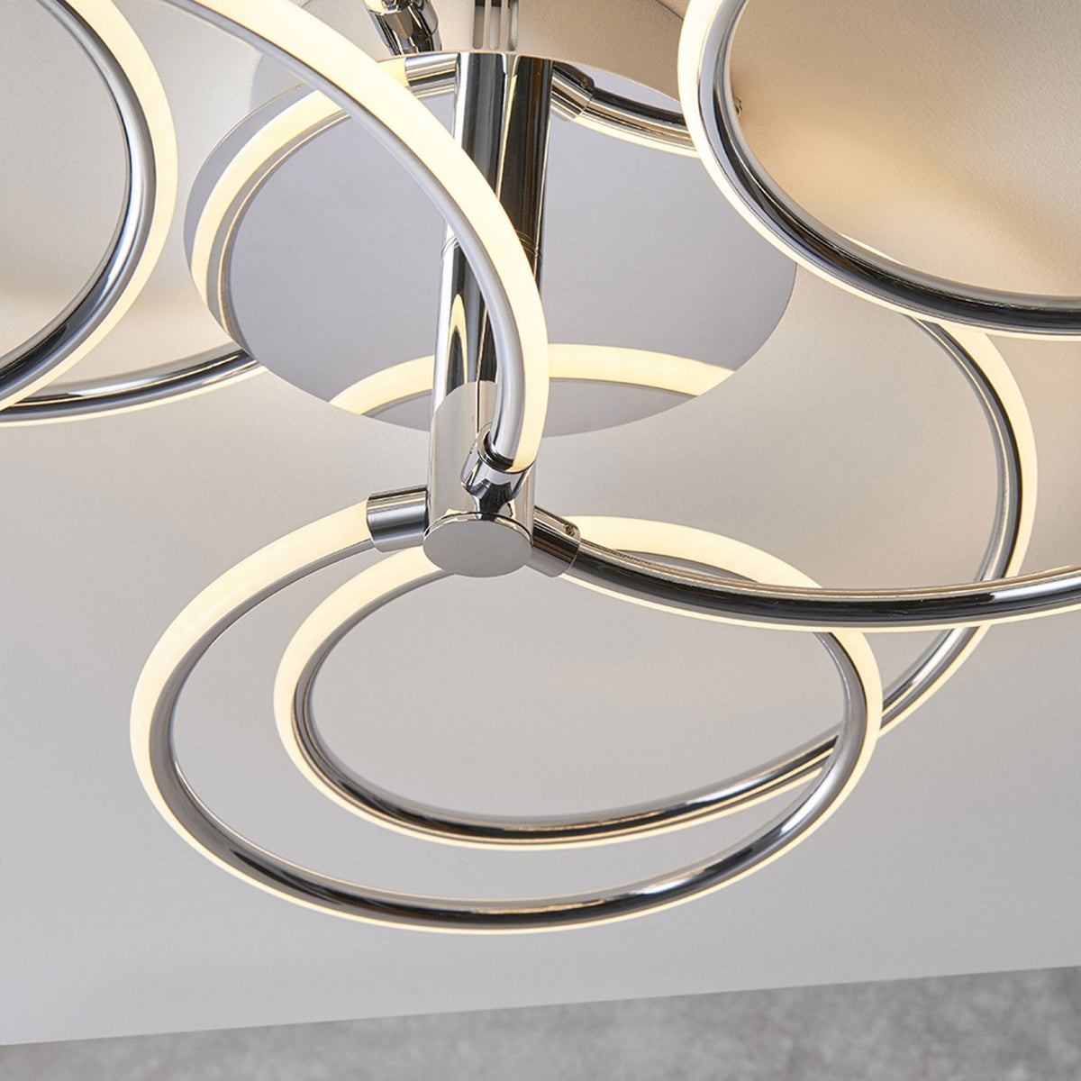 Underside view of a modern chrome ceiling light with illuminated rings.