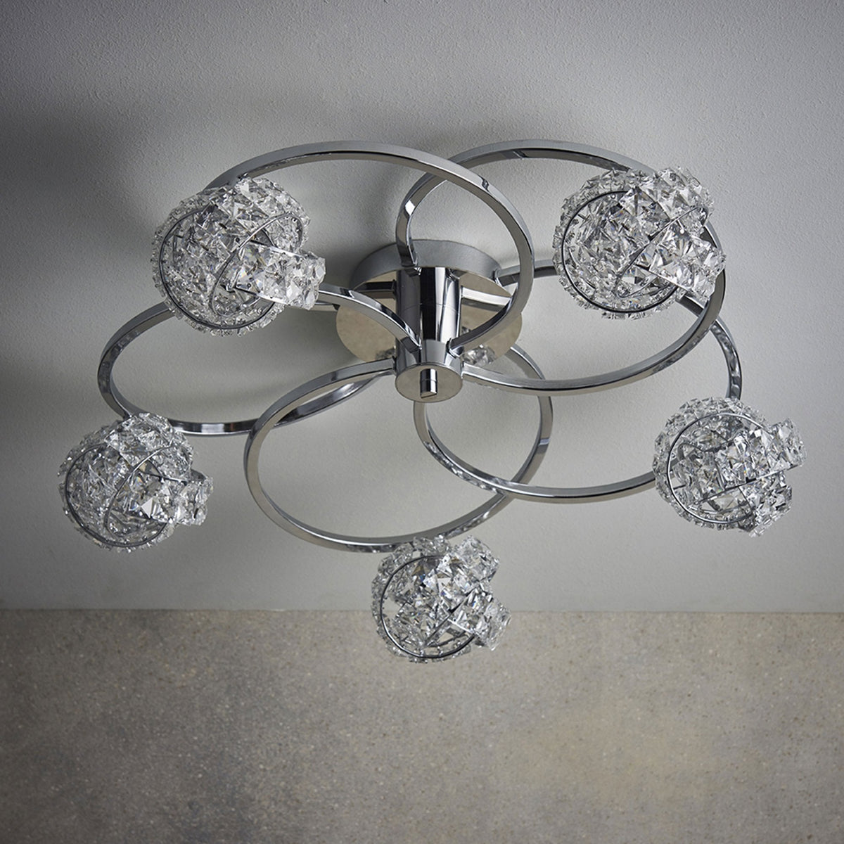 Chrome ceiling light with five crystal sphere shades, mounted on a white ceiling.