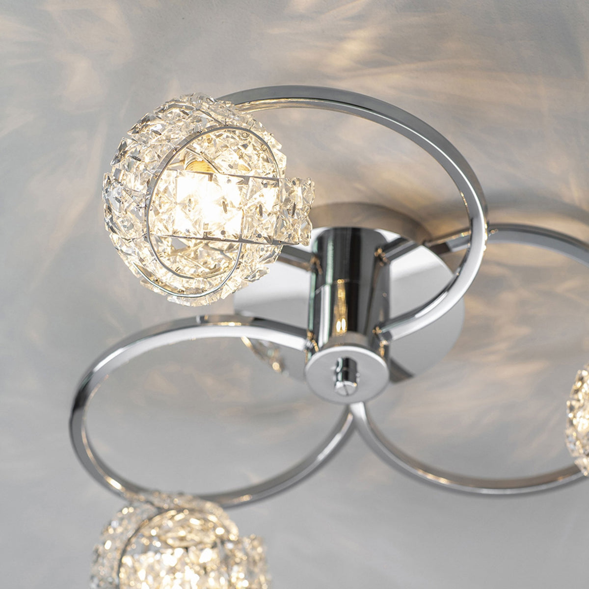 Close-up of a chrome ceiling light with a crystal orb shade, casting light patterns on the ceiling.