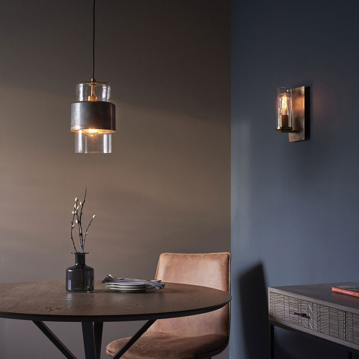 A room setting with a wall light and a pendant light, illuminating a dining area.
