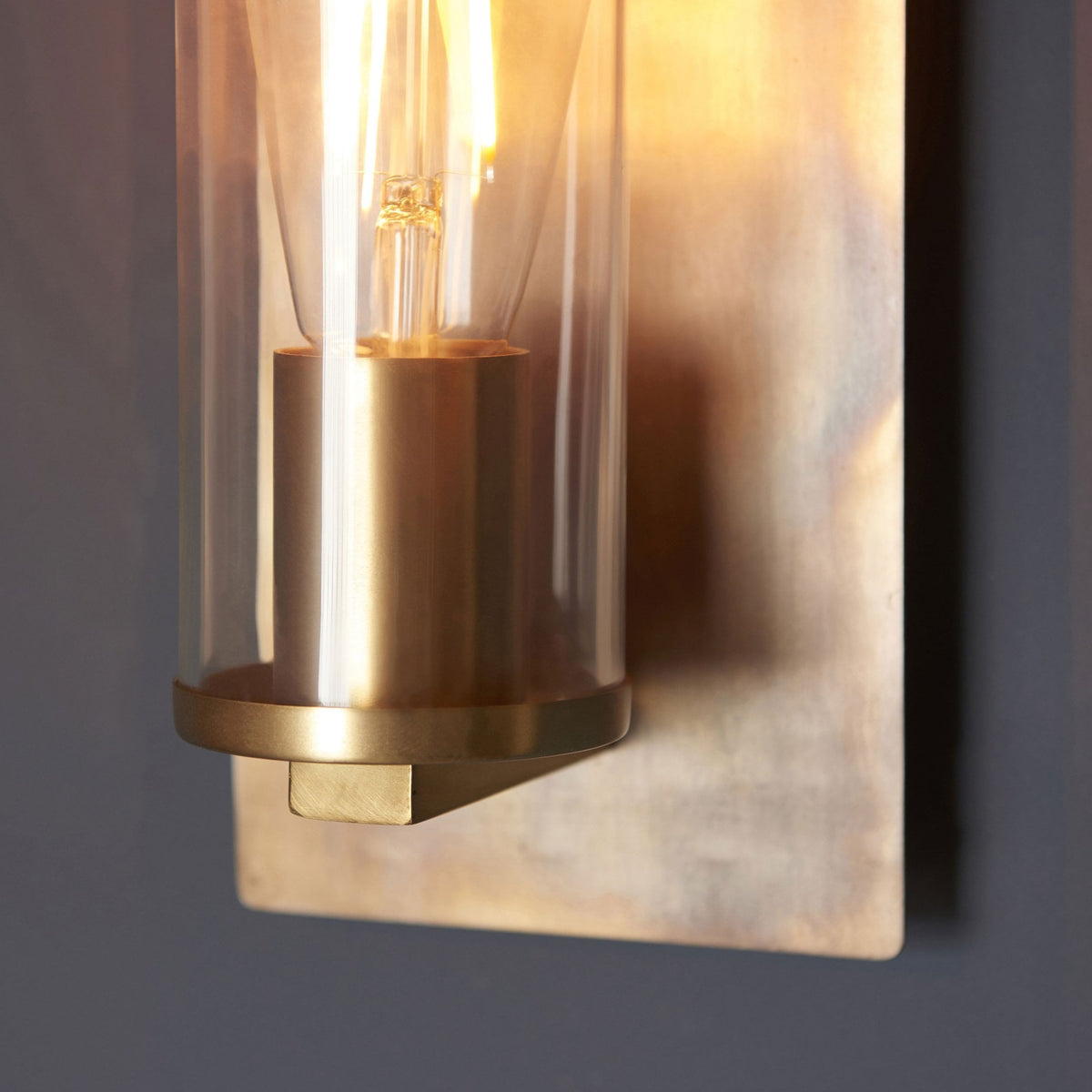 A detailed close-up of the wall light's brass base and the textured wall plate.