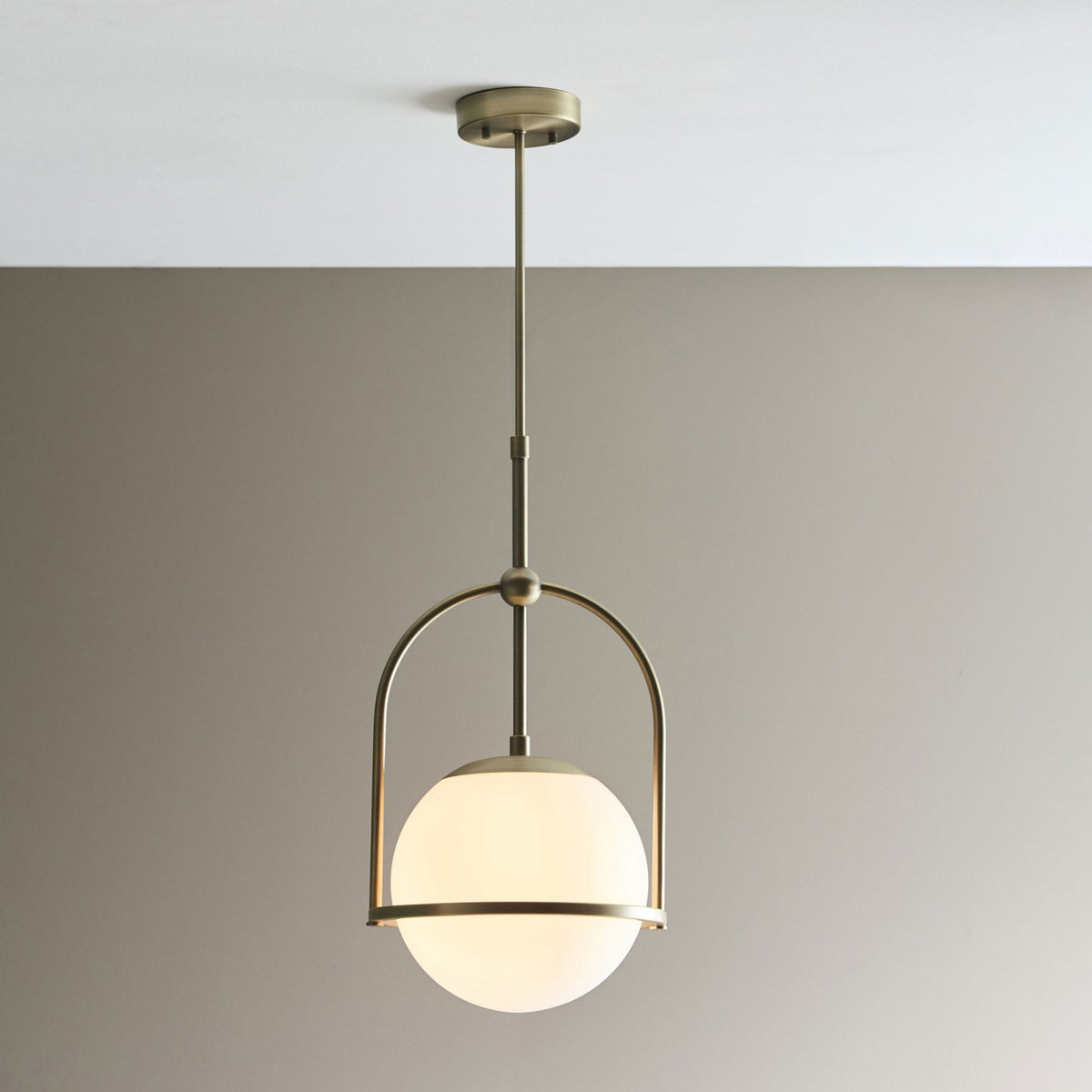 A modern bronze pendant light with a spherical white glass shade hangs from the ceiling.