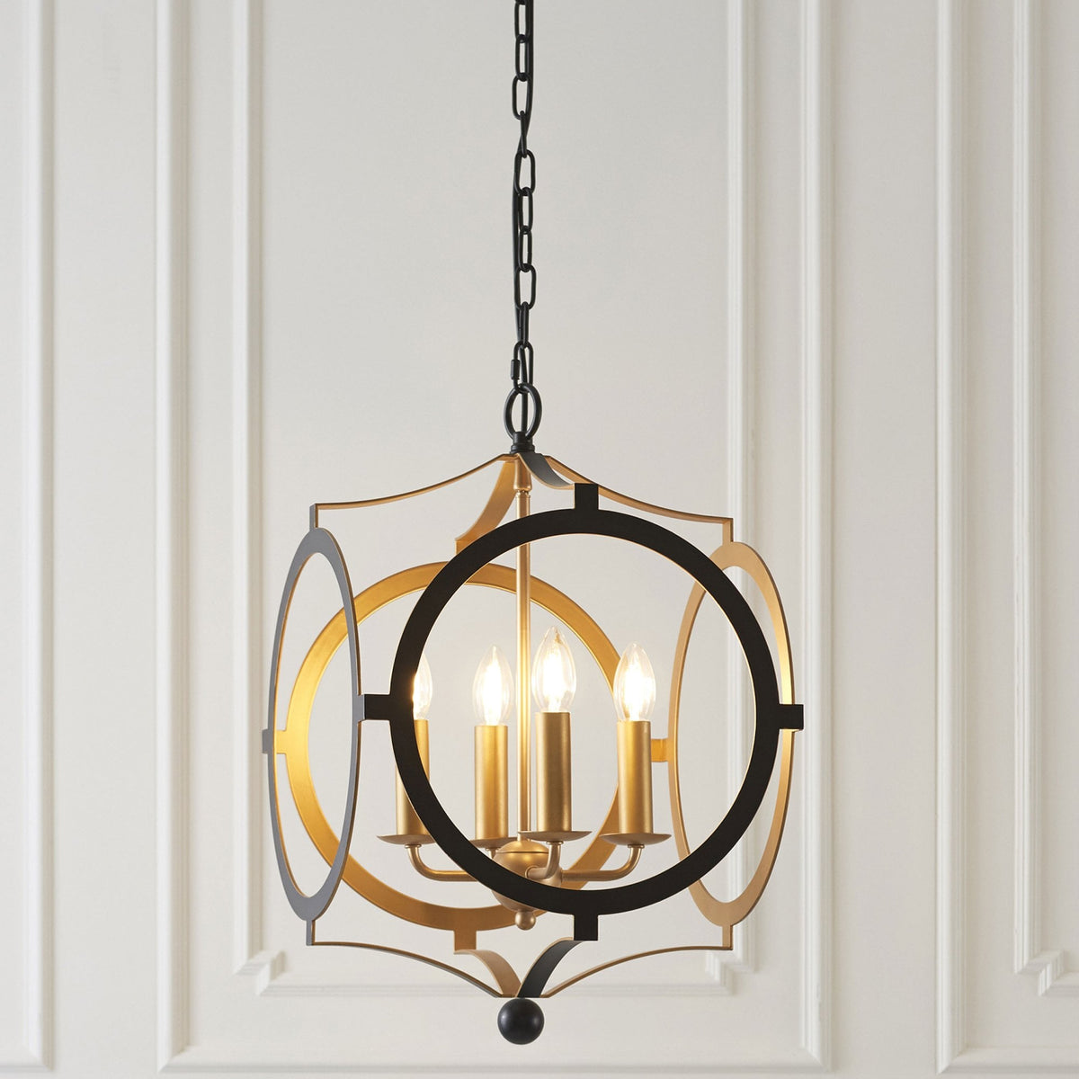 A black and gold chandelier hangs against a white paneled wall.