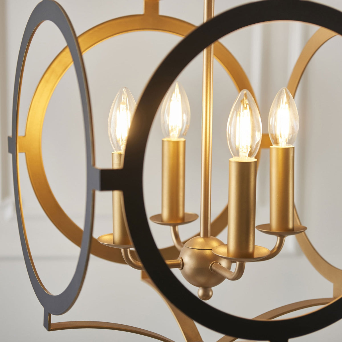 Close-up of the chandelier's illuminated candle-style bulbs and geometric gold and black frame.