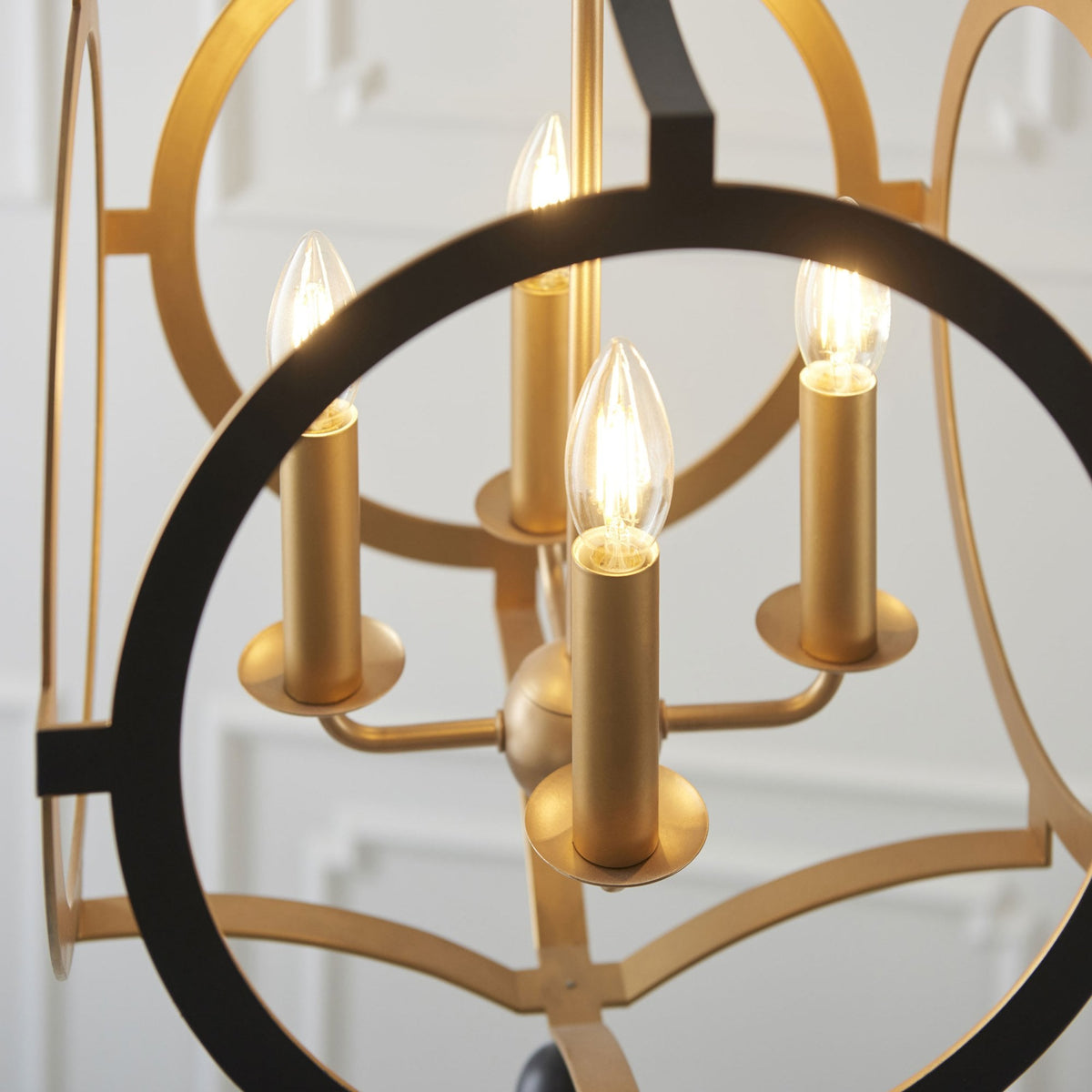 A close-up of the chandelier's golden candle-style lights and black and gold frame.