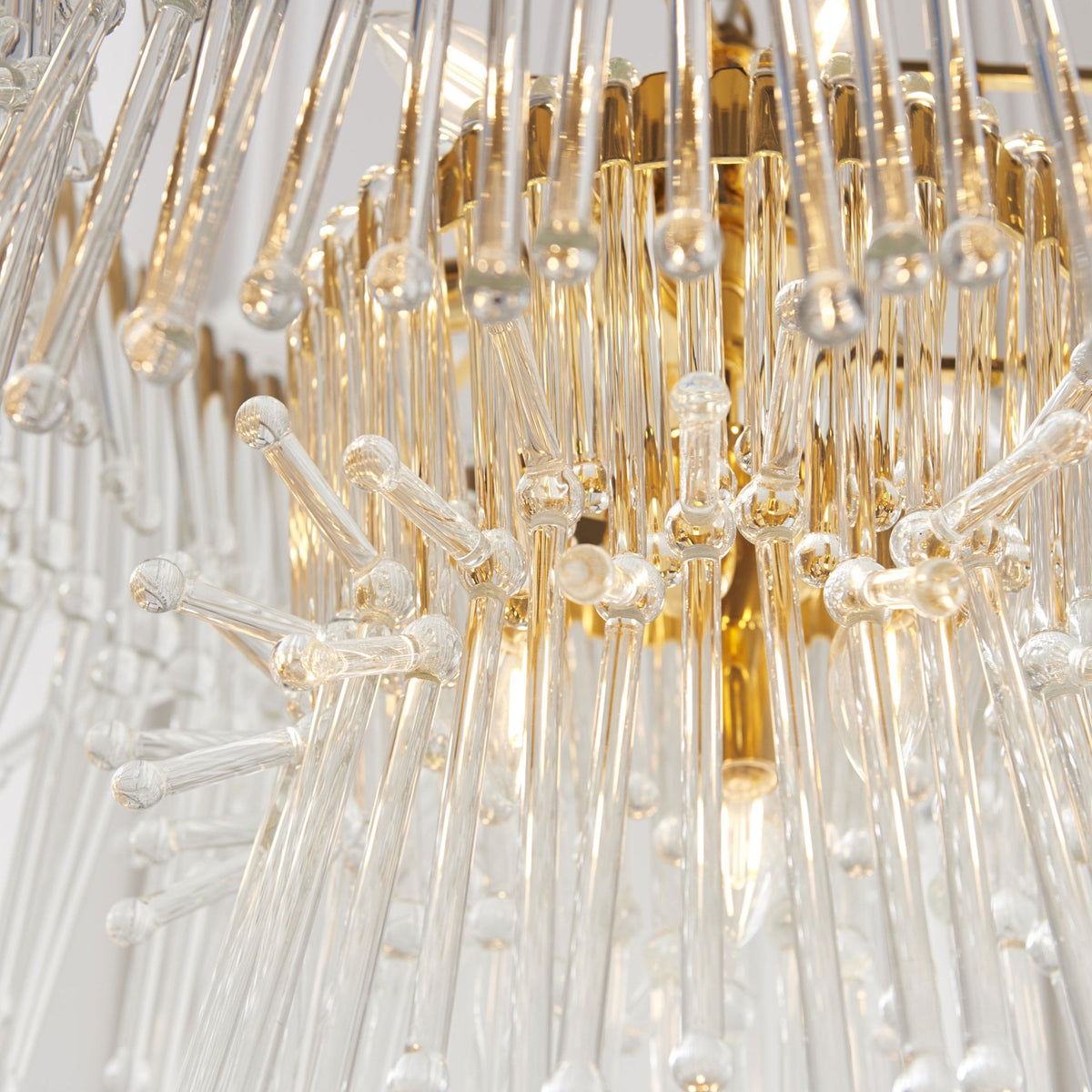 Close-up of the bottom tier of a gold and clear glass chandelier, showing individual glass rods.