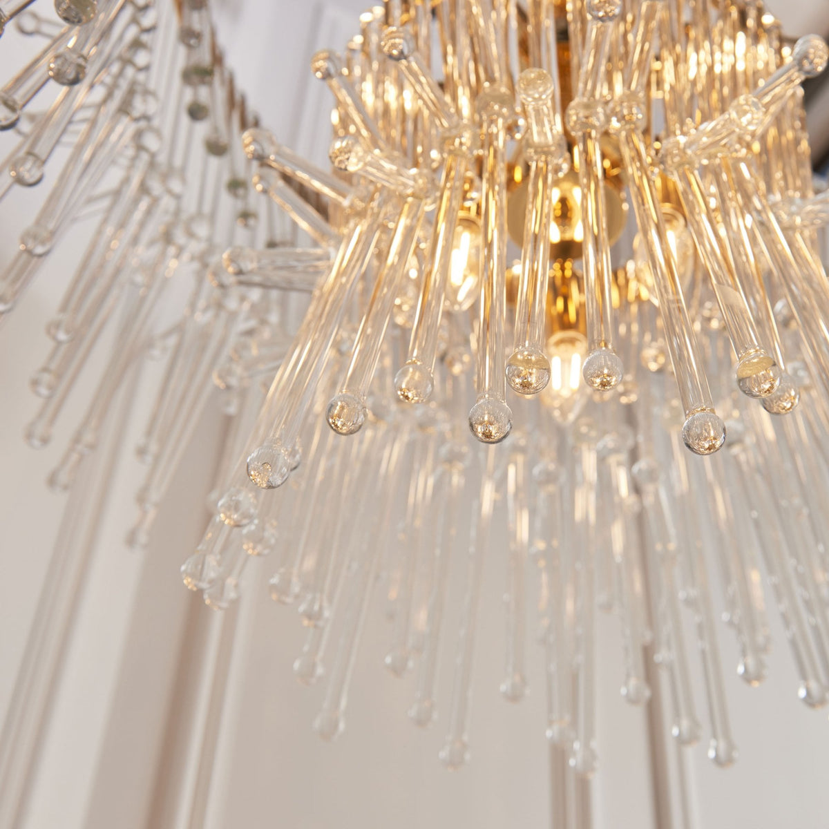 Angled close-up of the clear glass rods and illuminated gold interior of a chandelier.