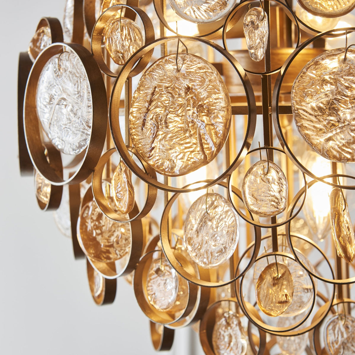 Detail of the gold chandelier, showcasing its intricate arrangement of clear and amber textured glass discs.
