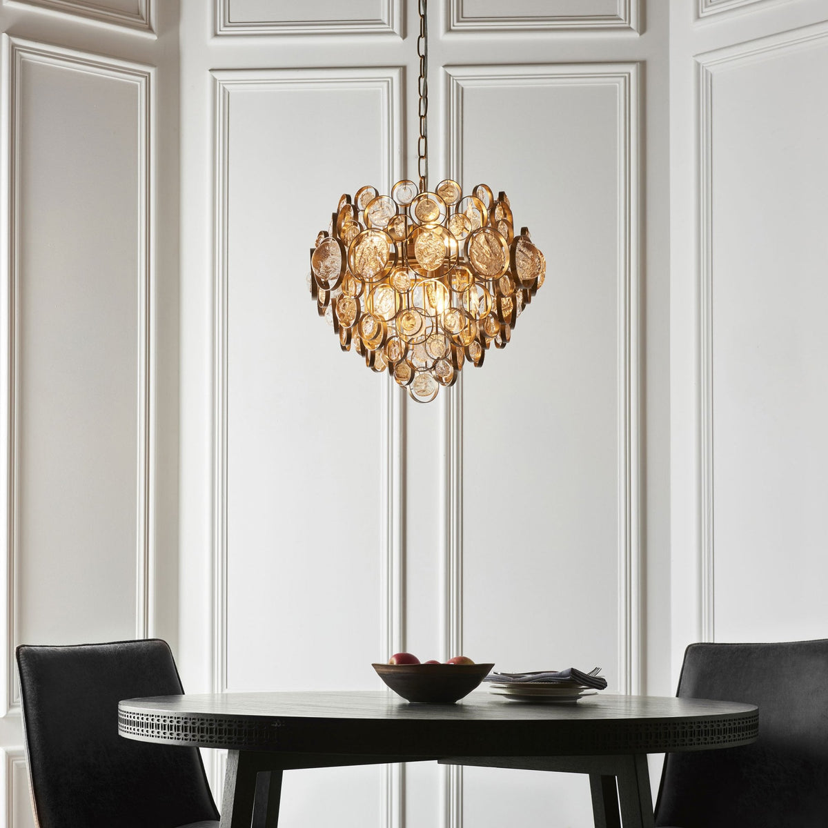 The gold chandelier adds a luxurious touch to a dining area with a round table and chairs.