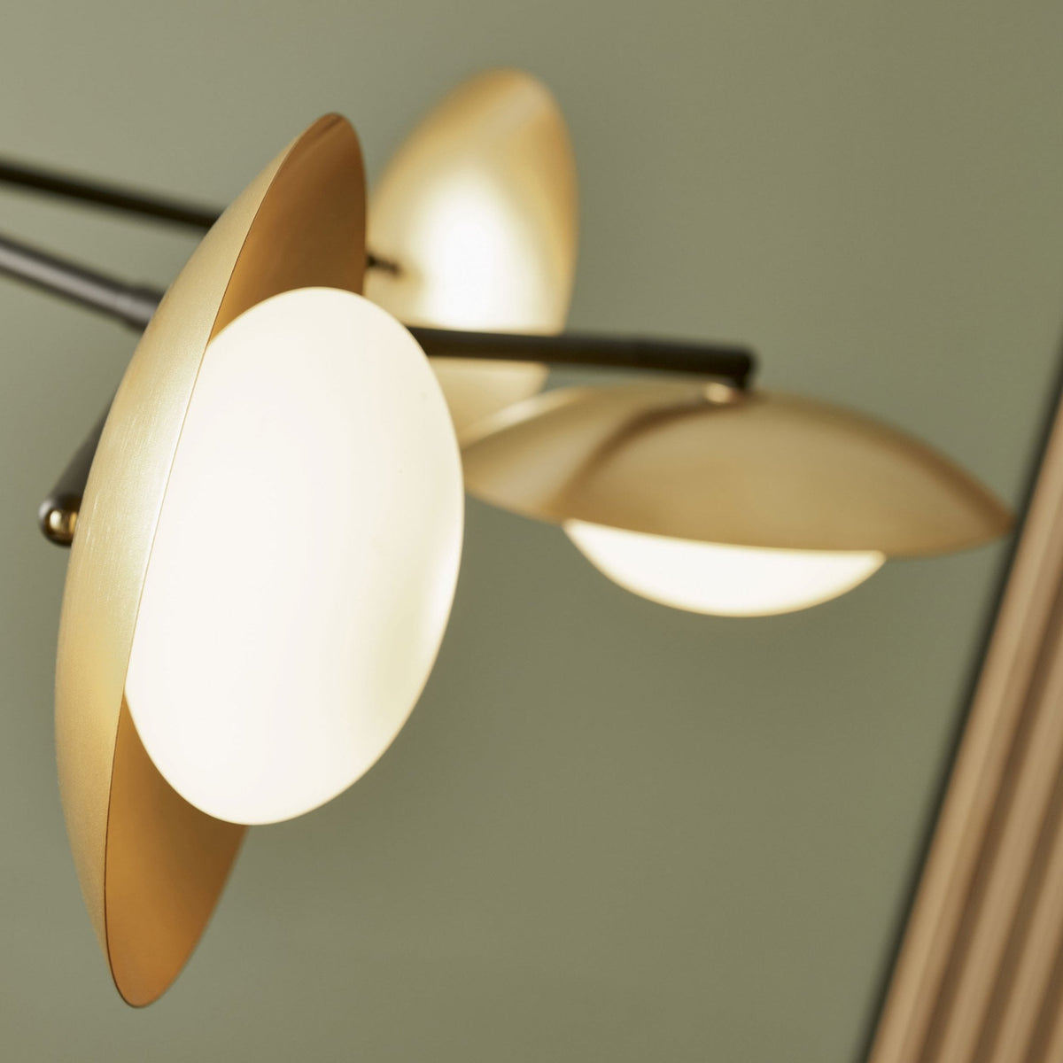 Close-up of two gold-toned, saucer-shaped light fixtures with white globes, showing their elegant design.