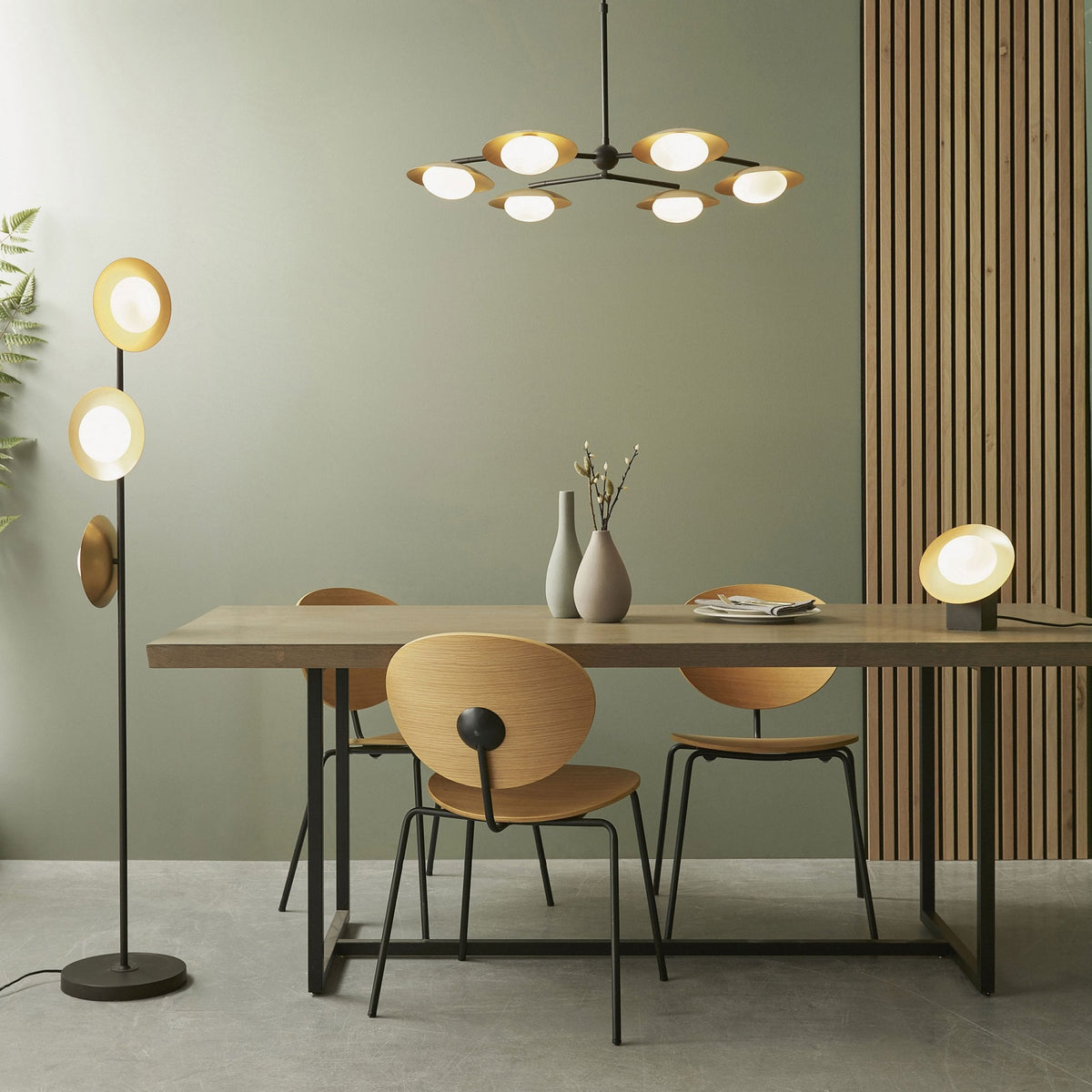 A modern dining room featuring a six-light chandelier, a floor lamp, and a table lamp with gold accents.