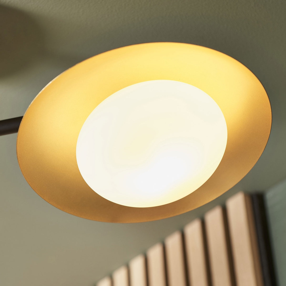 A close-up shot of a single illuminated spherical bulb, partially covered by a gold-colored metal shade.