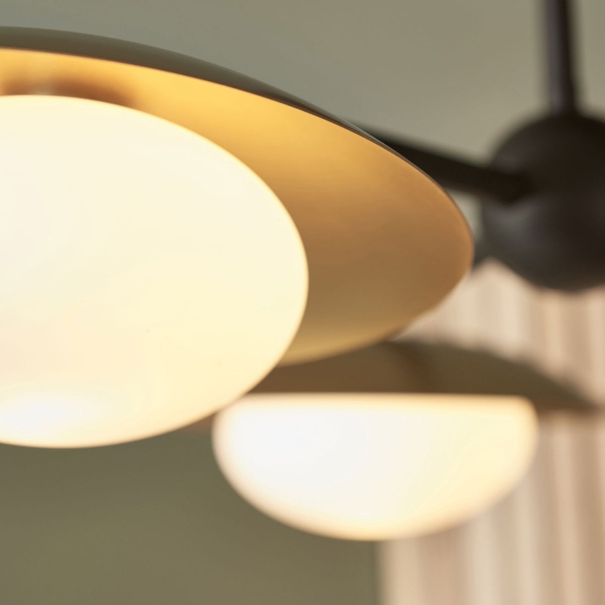 A detailed view of one spherical light bulb and its gold-toned shade, with another bulb in soft focus.