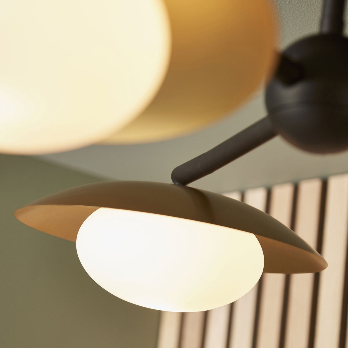 A close-up of a spherical light bulb with its gold shade, part of a multi-arm ceiling fixture.