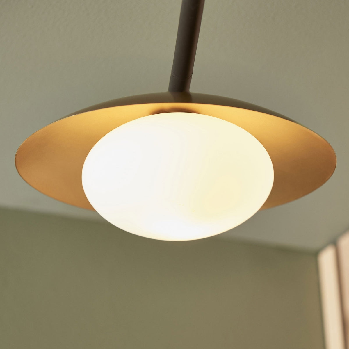A detailed shot of a single spherical light bulb nestled within its gold-colored metal shade.