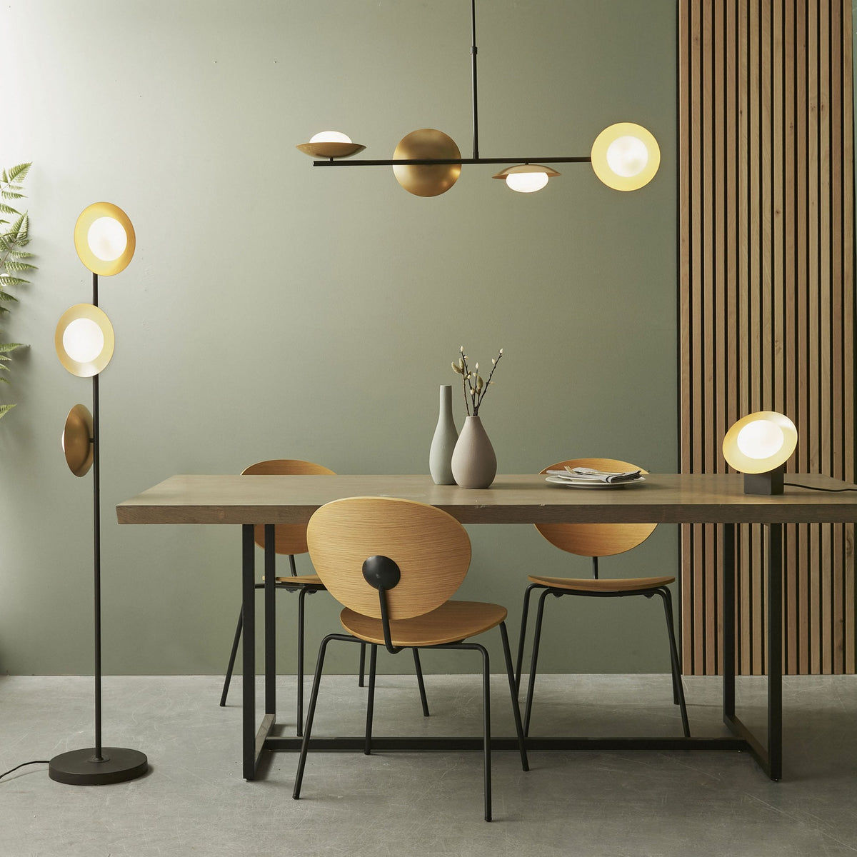 Dining room with a chandelier, floor lamp, and table lamp, all with disc-shaped lights.
