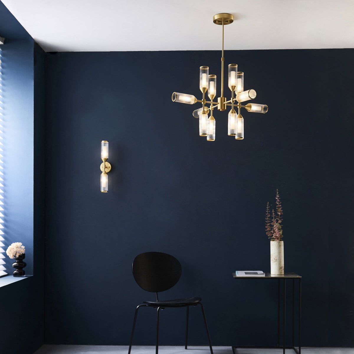 A room with a blue wall, featuring a brass wall light and a matching chandelier.