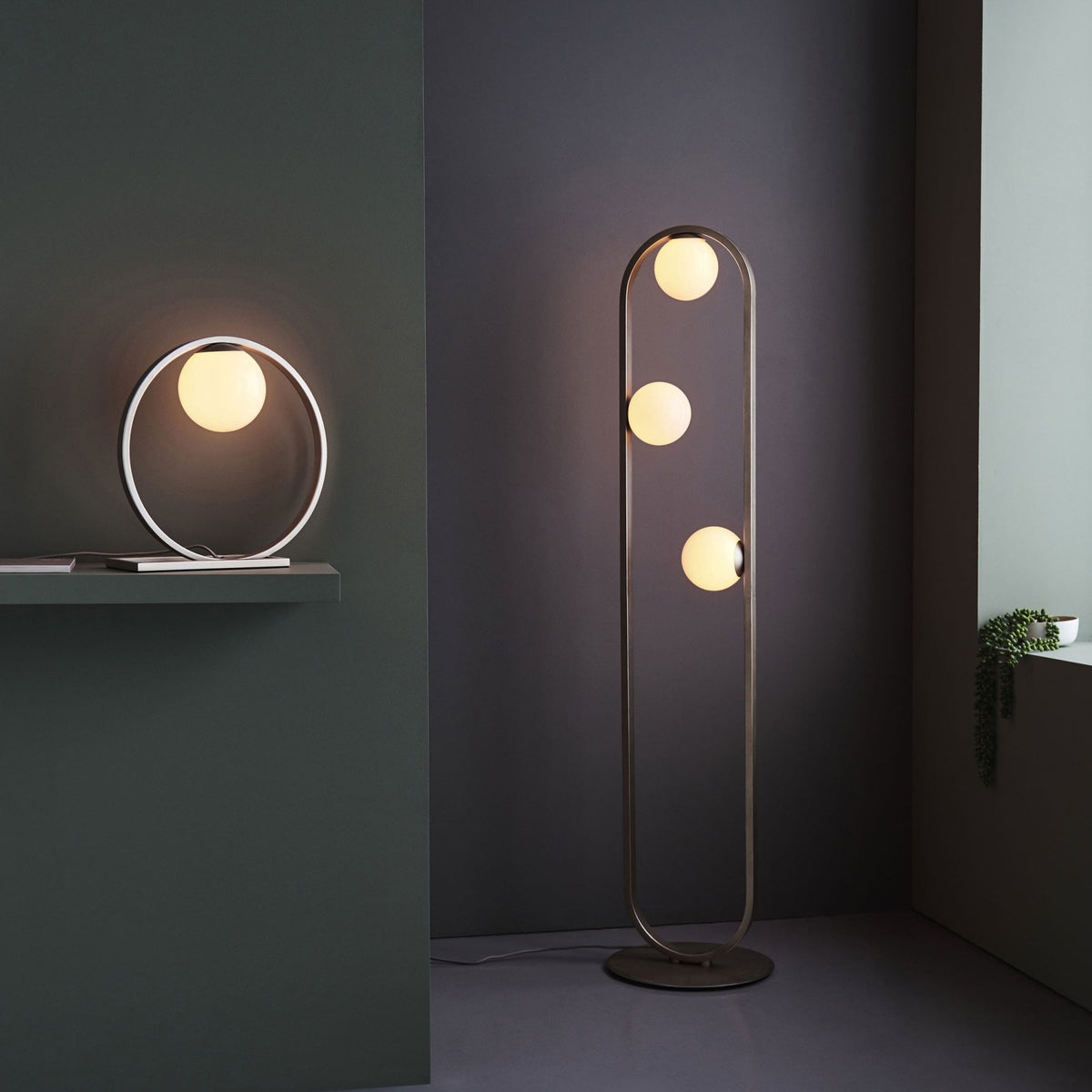 Modern table lamp and floor lamp with spherical bulbs and brushed metal frames in a dark room.