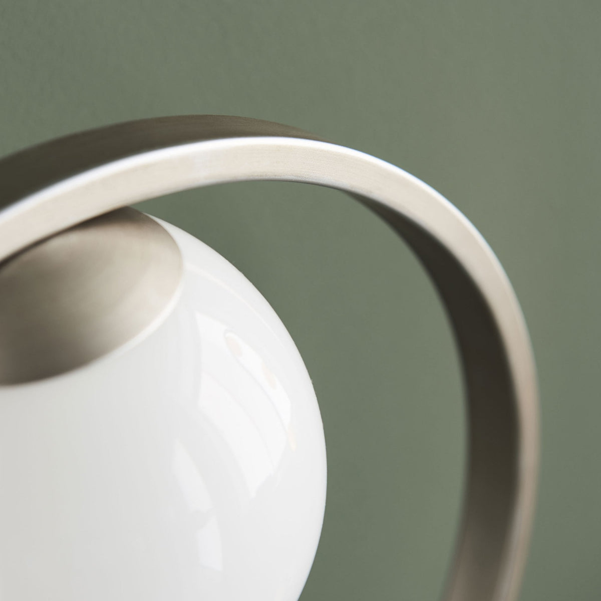Close-up of the spherical bulb and brushed metal frame of a modern table lamp, unlit.