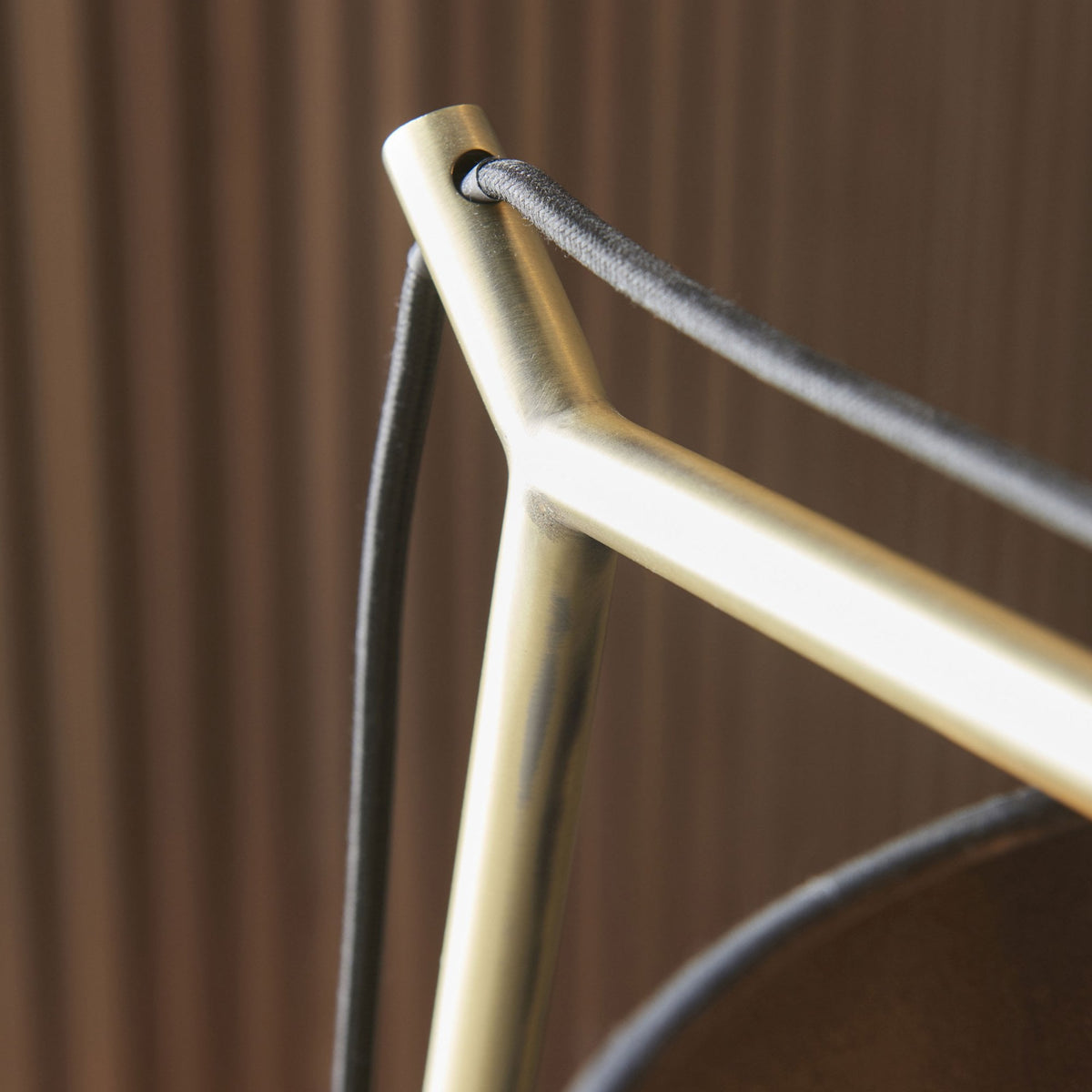 Close-up of the gold-colored frame and black wire detail of a modern desk lamp.