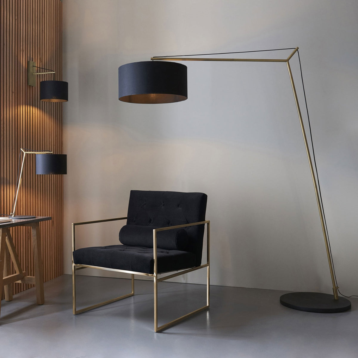 A modern living space featuring a black and gold floor lamp, desk lamp, and wall lamp with a black armchair.