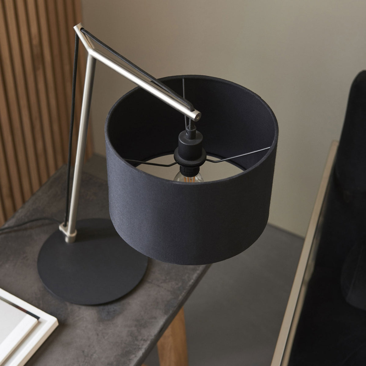 Overhead view of a black and gold table lamp with a silver frame on a dark gray table.