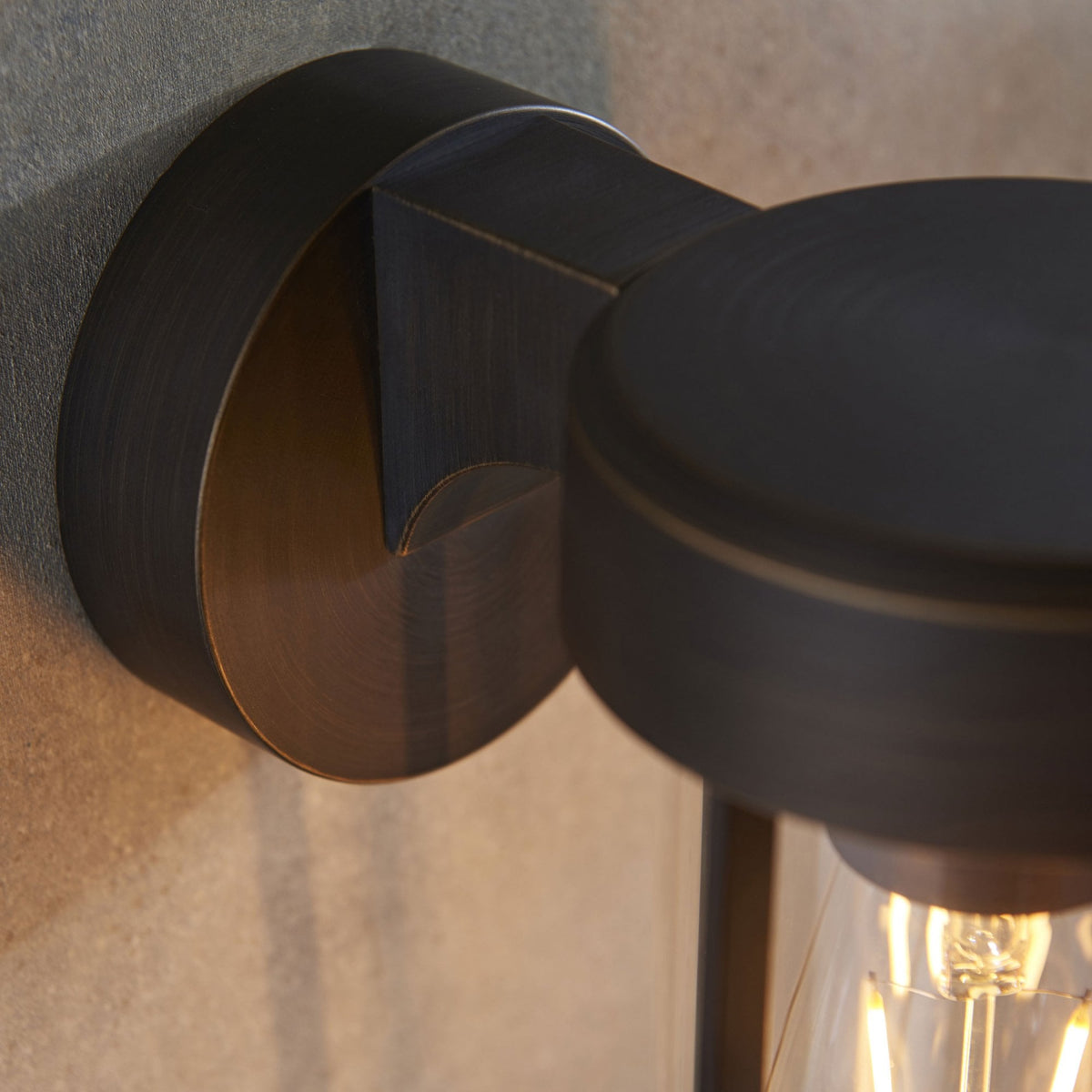 Gros plan de la base d'une applique murale noire, de forme cylindrique, pour l'extérieur ou la salle de bain.