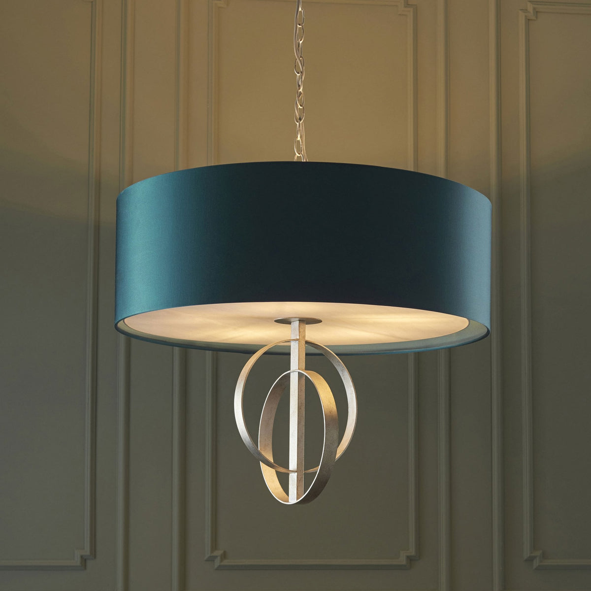 A teal drum shade pendant light featuring an openwork silver orbit design hanging in a classic room.