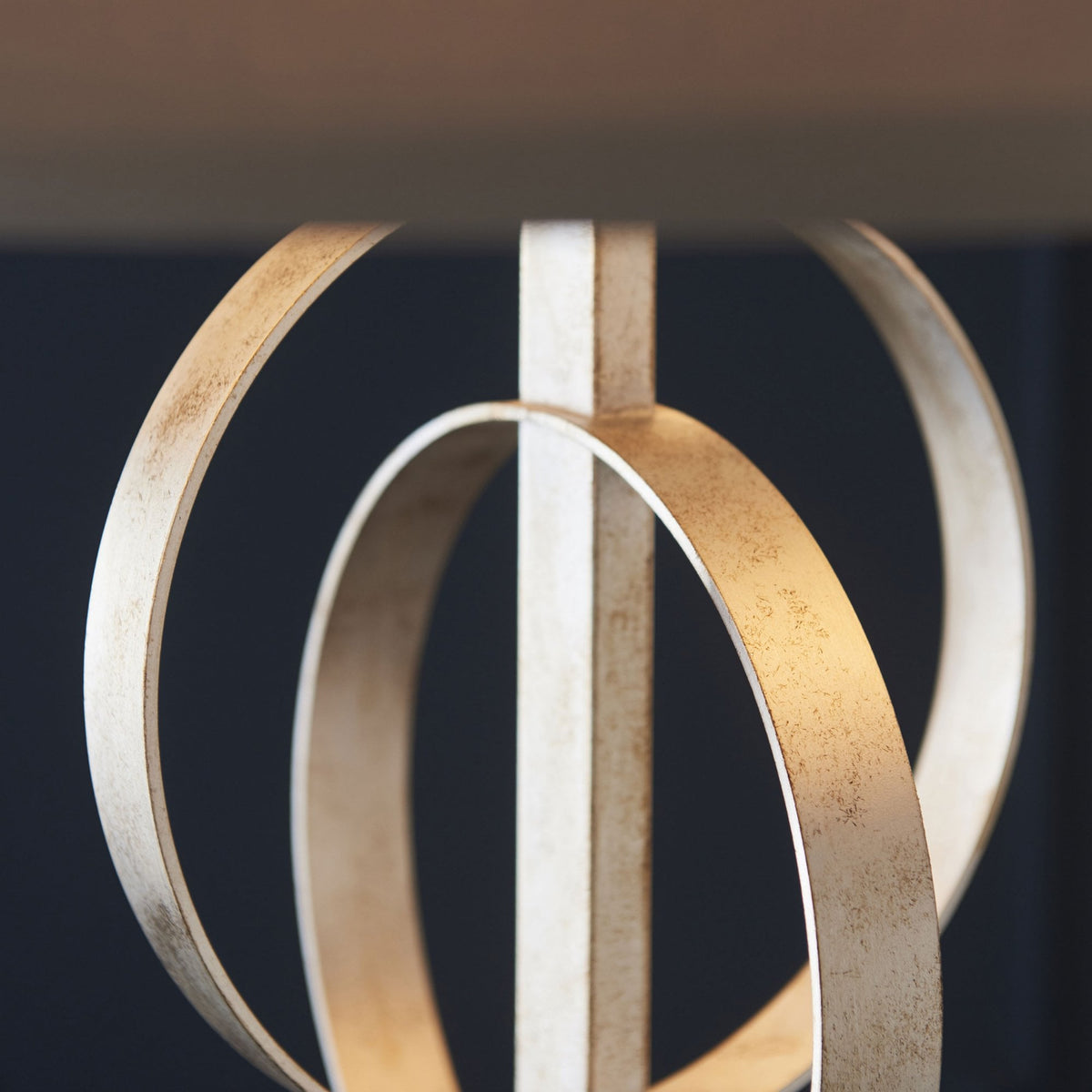 Detailed close-up of the champagne gold intertwined metallic rings of the pendant light.