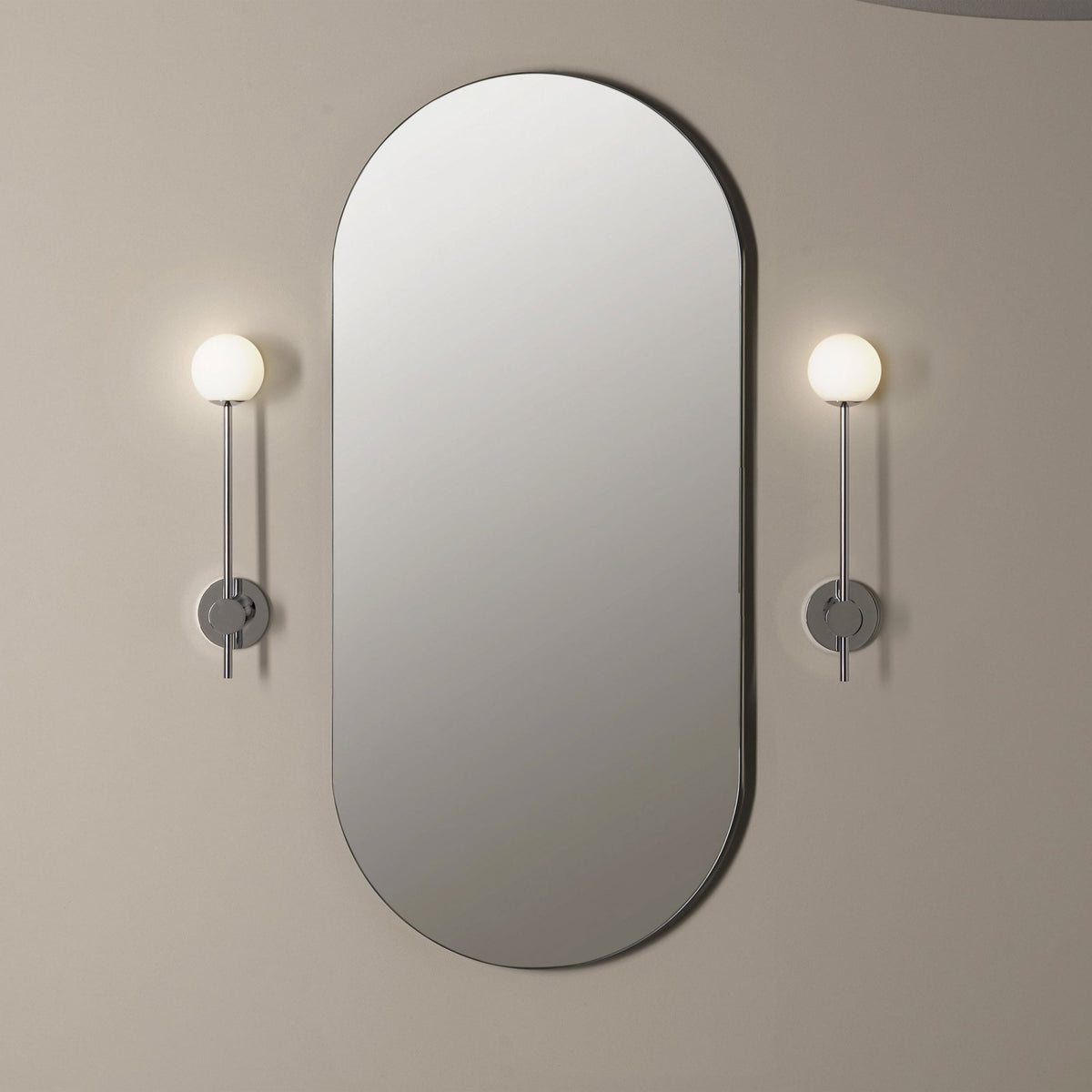 Oval mirror with two wall-mounted globe lights on either side