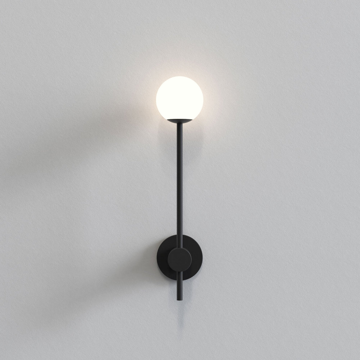 Black wall sconce with a glowing spherical light on a light grey wall