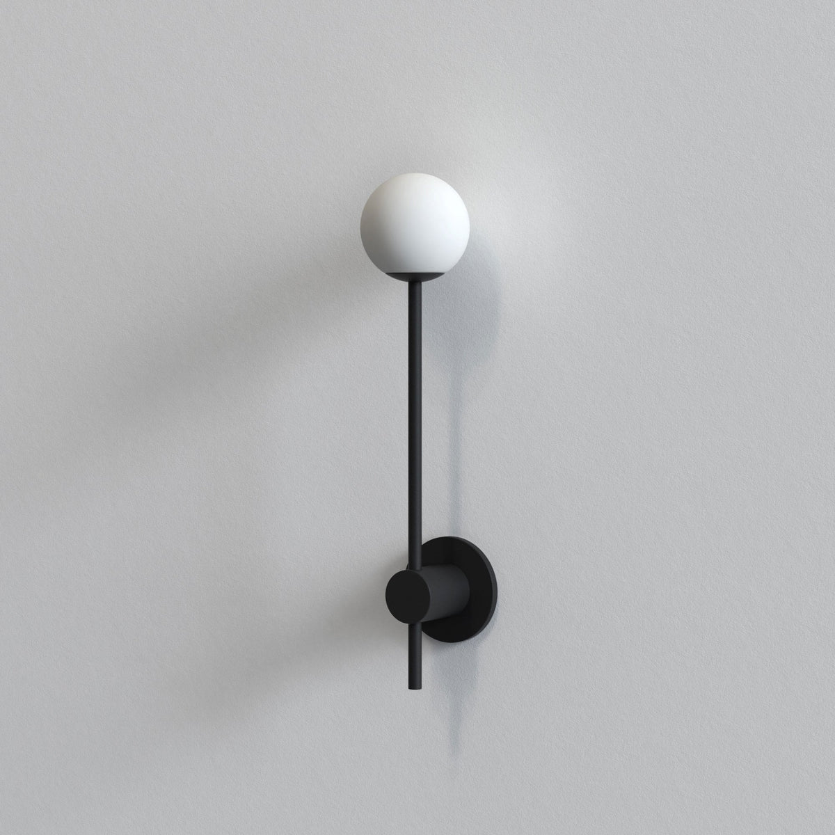 Black wall sconce with a white spherical light on a light gray wall