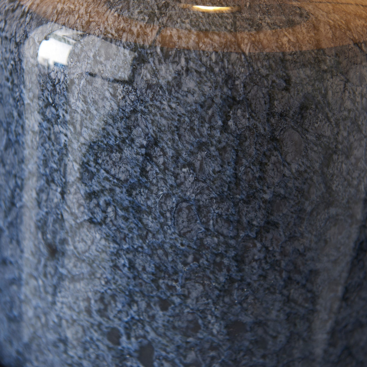 A close-up of the textured blue glazed ceramic base of the table lamp.