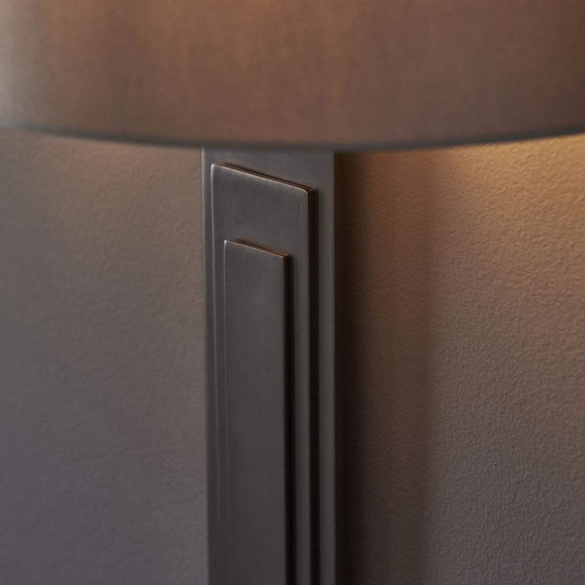 A close-up of the rectangular base of a grey wall light, showcasing its layered, geometric design.