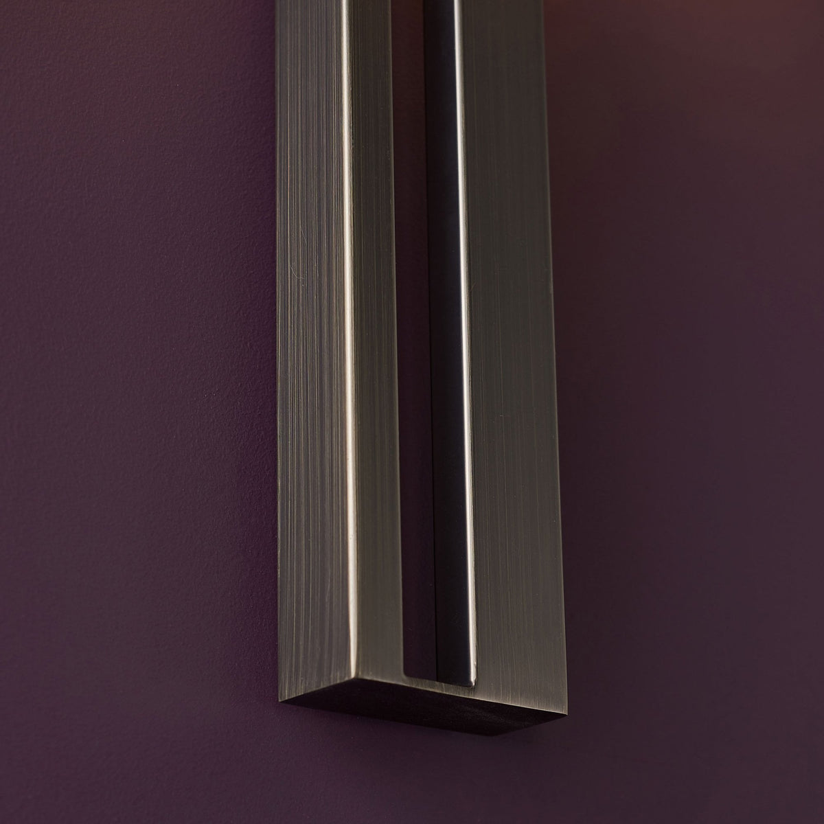 Close-up of the textured bronze rectangular base of a wall-mounted light fixture.
