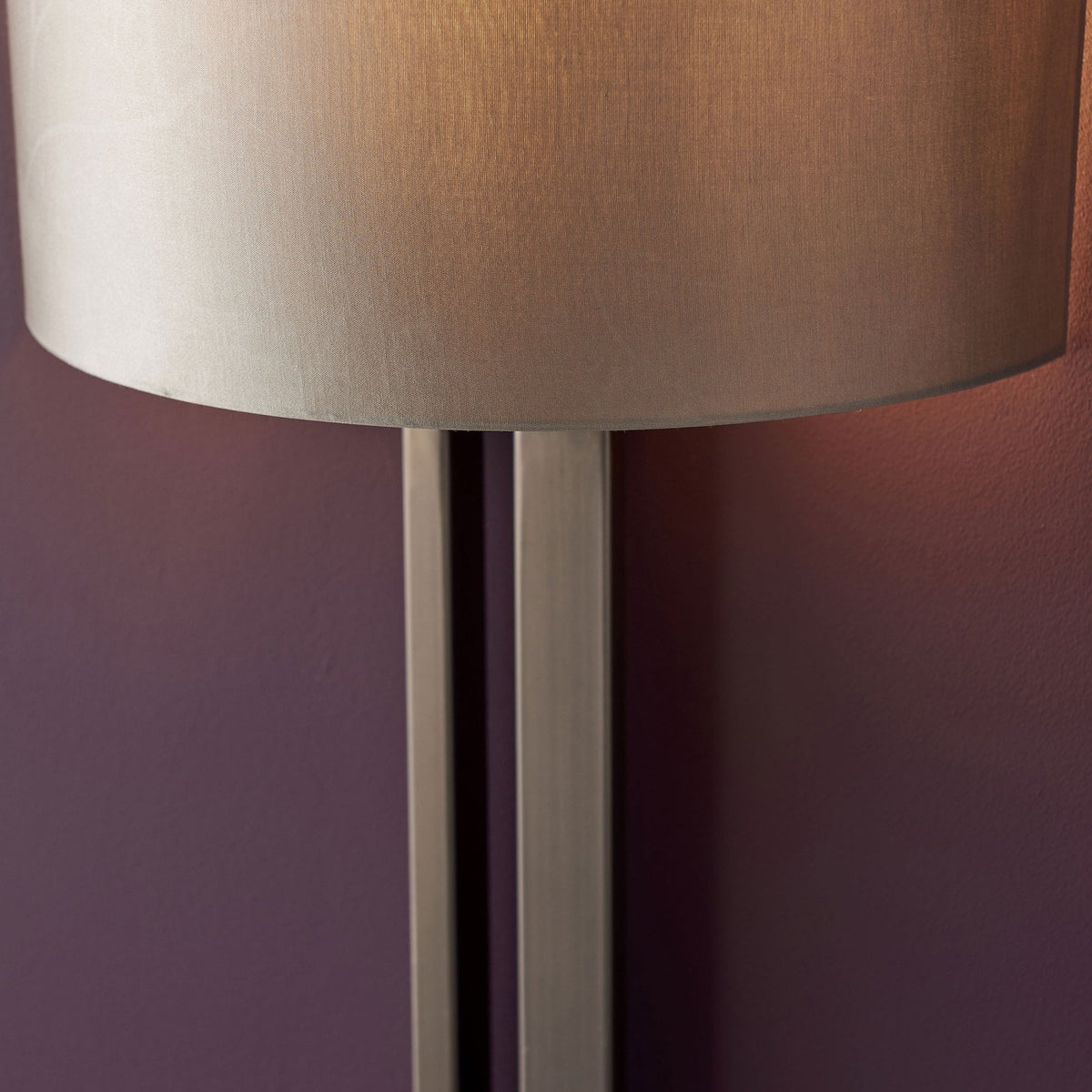 Close-up of the beige cylindrical shade and bronze rectangular base of a modern wall light.